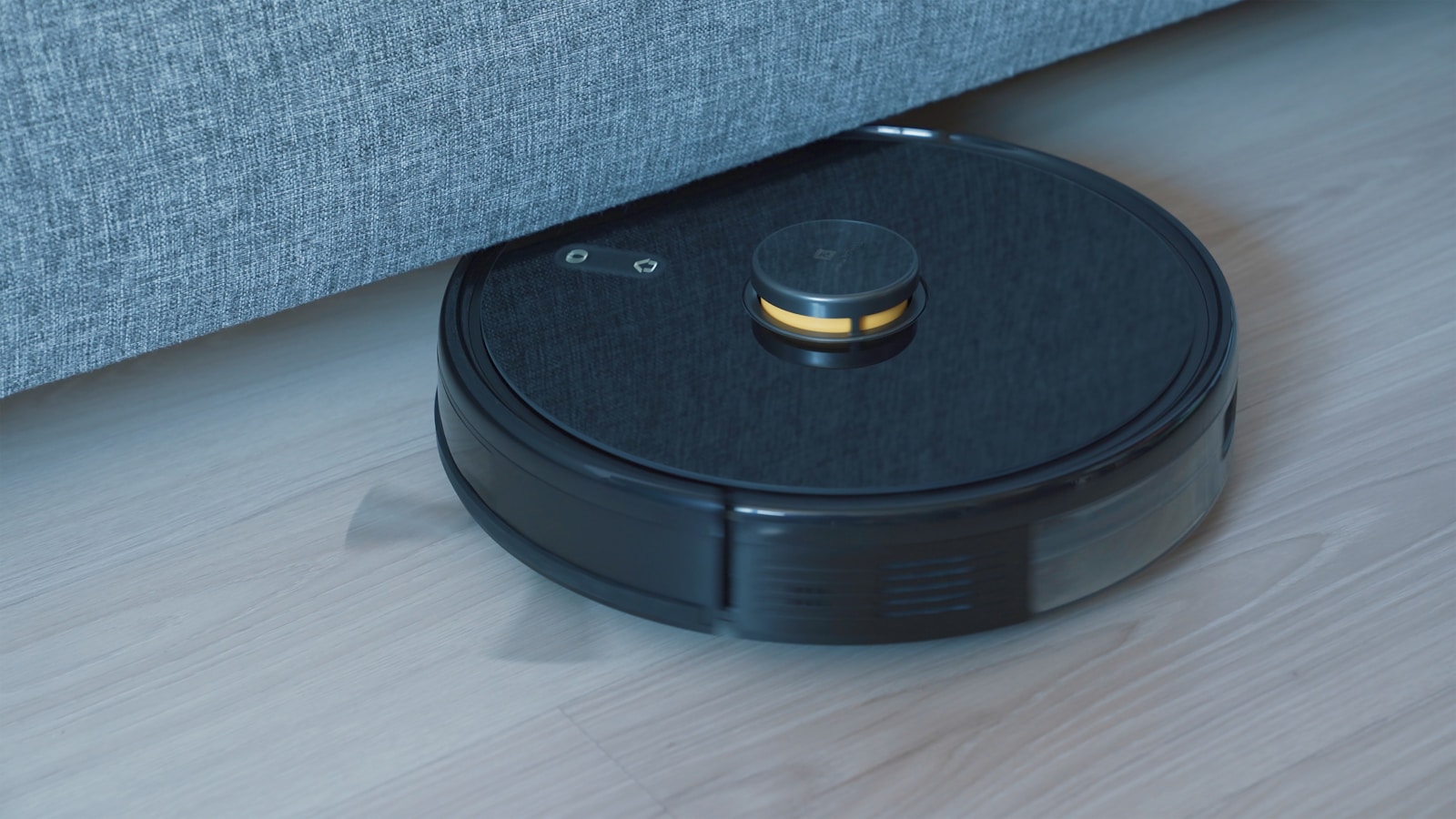 木製床を走る黒いロボット掃除機